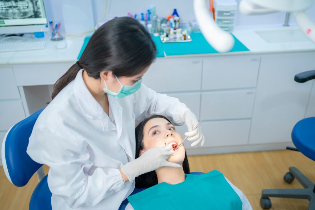 Asian female dentist in lab coat wearing protective face mask to prevent from Covid19.